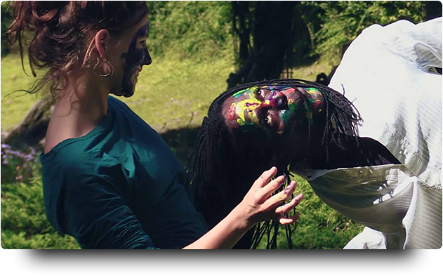 Tänzer sitzen auf Stein und bemalen sich mit Farbe